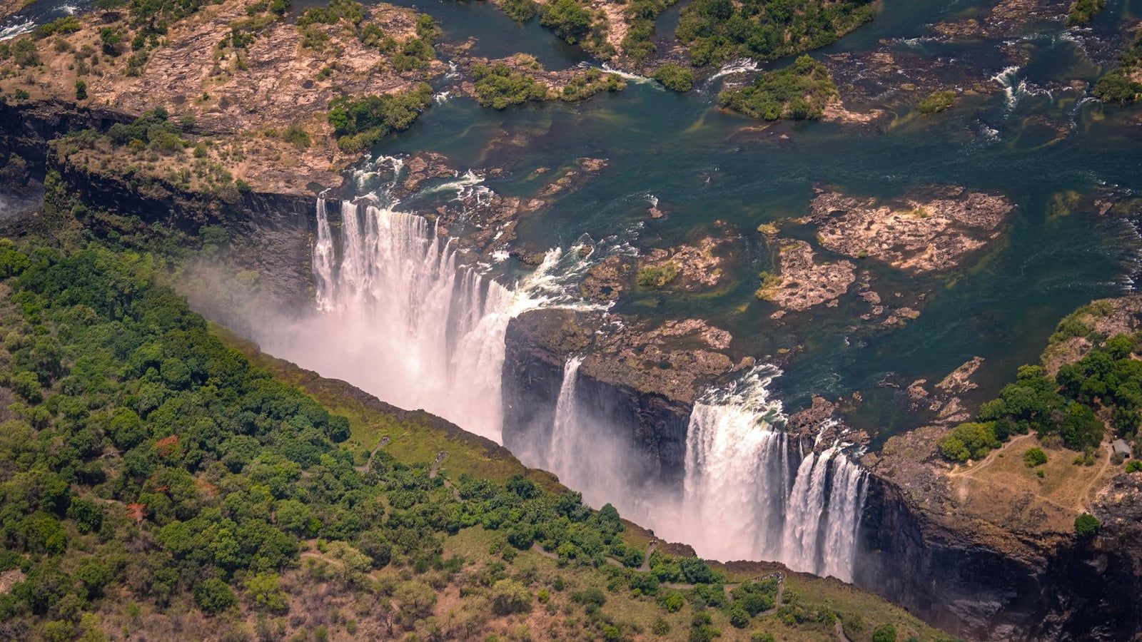 Vista aérea de las cataratas Victoria cayendo en picado hacia un profundo desfiladero rocoso en el río Zambeze.